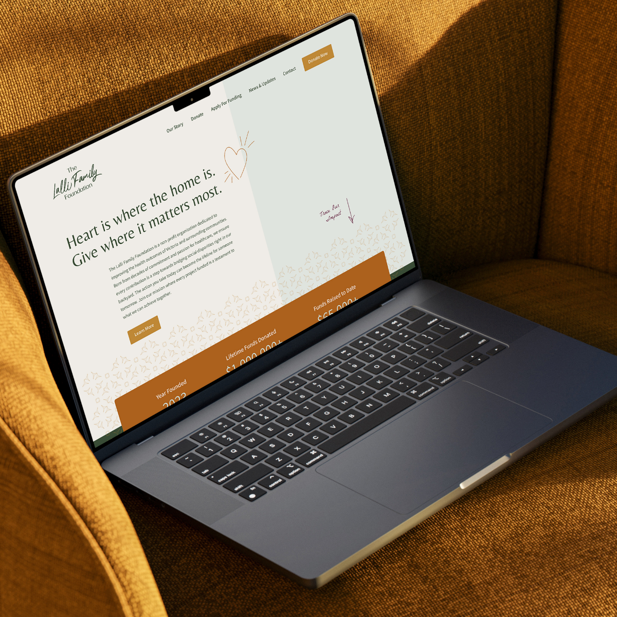 Laptop displaying a non profit marketing website with the headline “Heart is where the home is,” positioned on a mustard yellow chair – evoking warmth, trust, and a mission-driven brand identity.